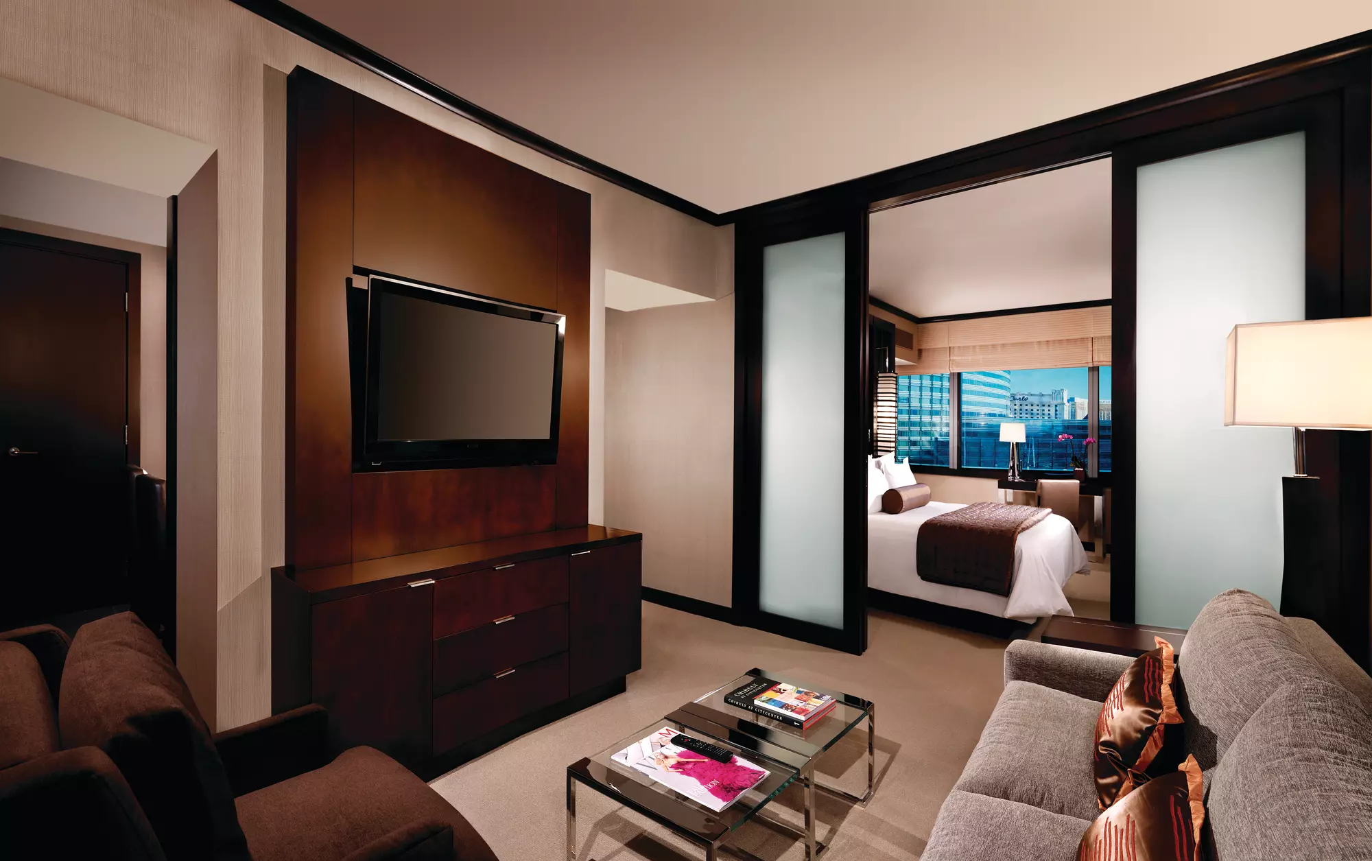 Room at the Vdara at ARIA with a living room with a couch and television separated from a bedroom with a queen-sized bed by glass, frosted doors.